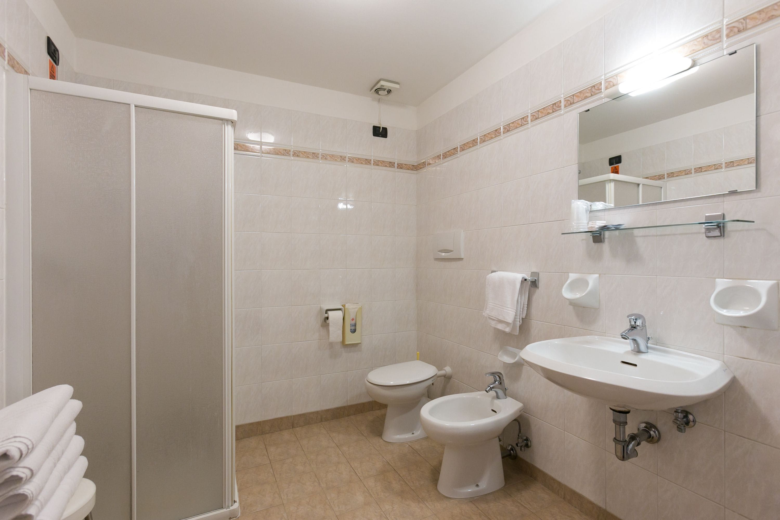 Un baño con ducha, inodoro, bidé y lavamanos.