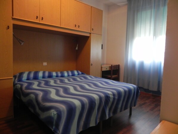 Une chambre à coucher avec un lit, une armoire en bois et un petit bureau.