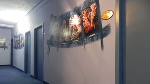 A hallway with a mural on the wall, a door, and a sign indicating the piano room. - Hotel Antonella (Caorle)