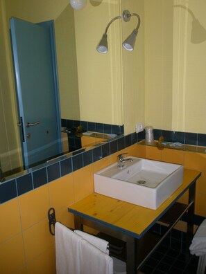 A bathroom with a blue door, a white sink, and a mirror above it. - Hotel Antonella (Caorle)