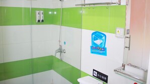 Une salle de bain avec des carreaux verts et blancs, une douche en verre, un porte-serviettes et un sèche-mains.