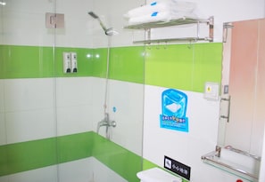 Un baño con baldosas verde y blanco, un cerramiento de ducha de vidrio, un perchero y un secador de manos.