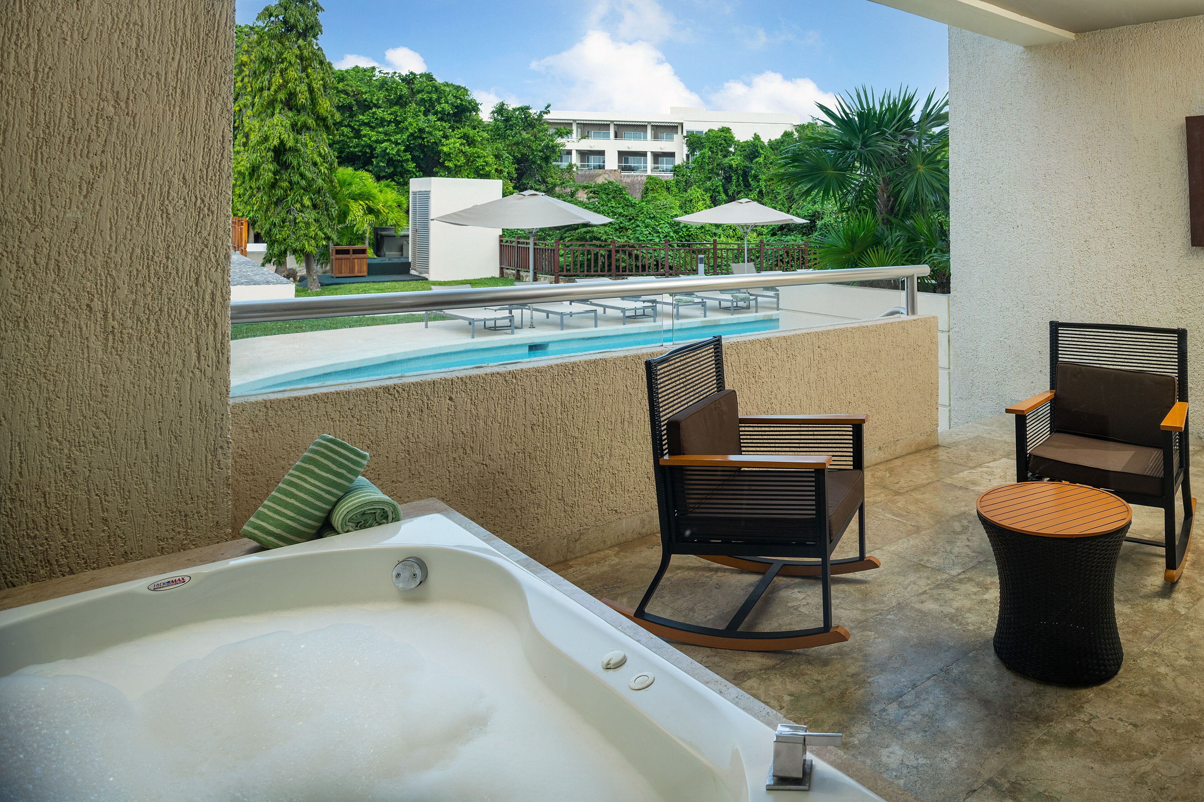 A balcony with a hot tub, two rocking chairs, and a small round table.