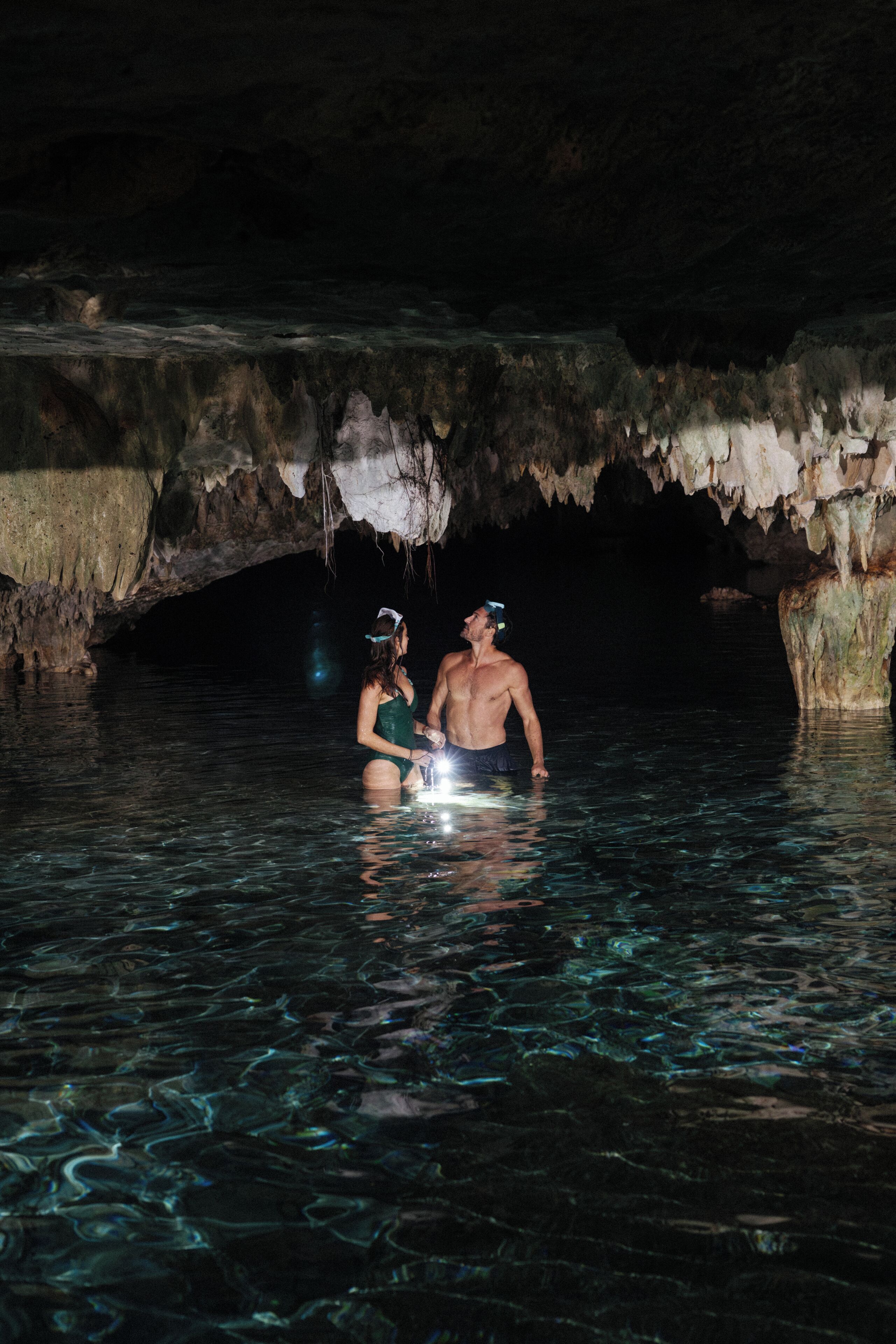 Dos personas en un entorno acuático que recuerda a una cueva, con estalactitas.
