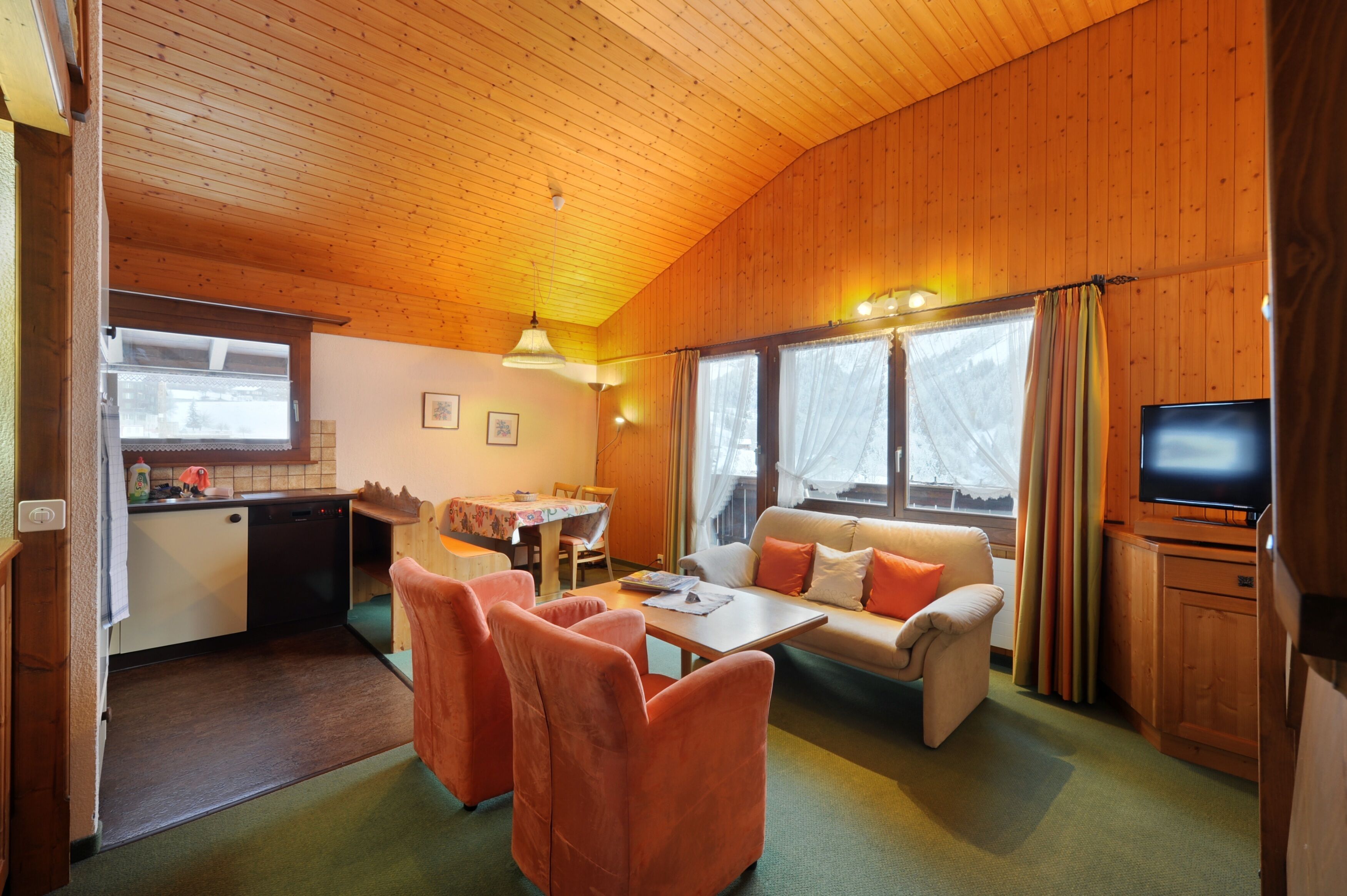 A cozy cabin interior with a dining area, sofa, and television.