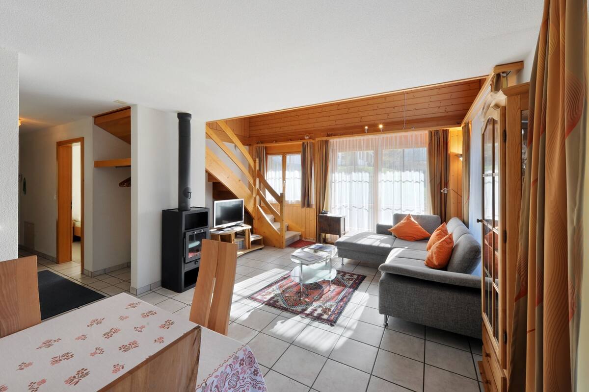 Una sala de estar moderna con un sofá, una mesa de centro, una chimenea y una escalera.