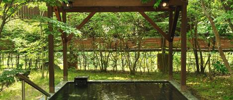 A wooden structure with a pool, surrounded by lush greenery and trees.