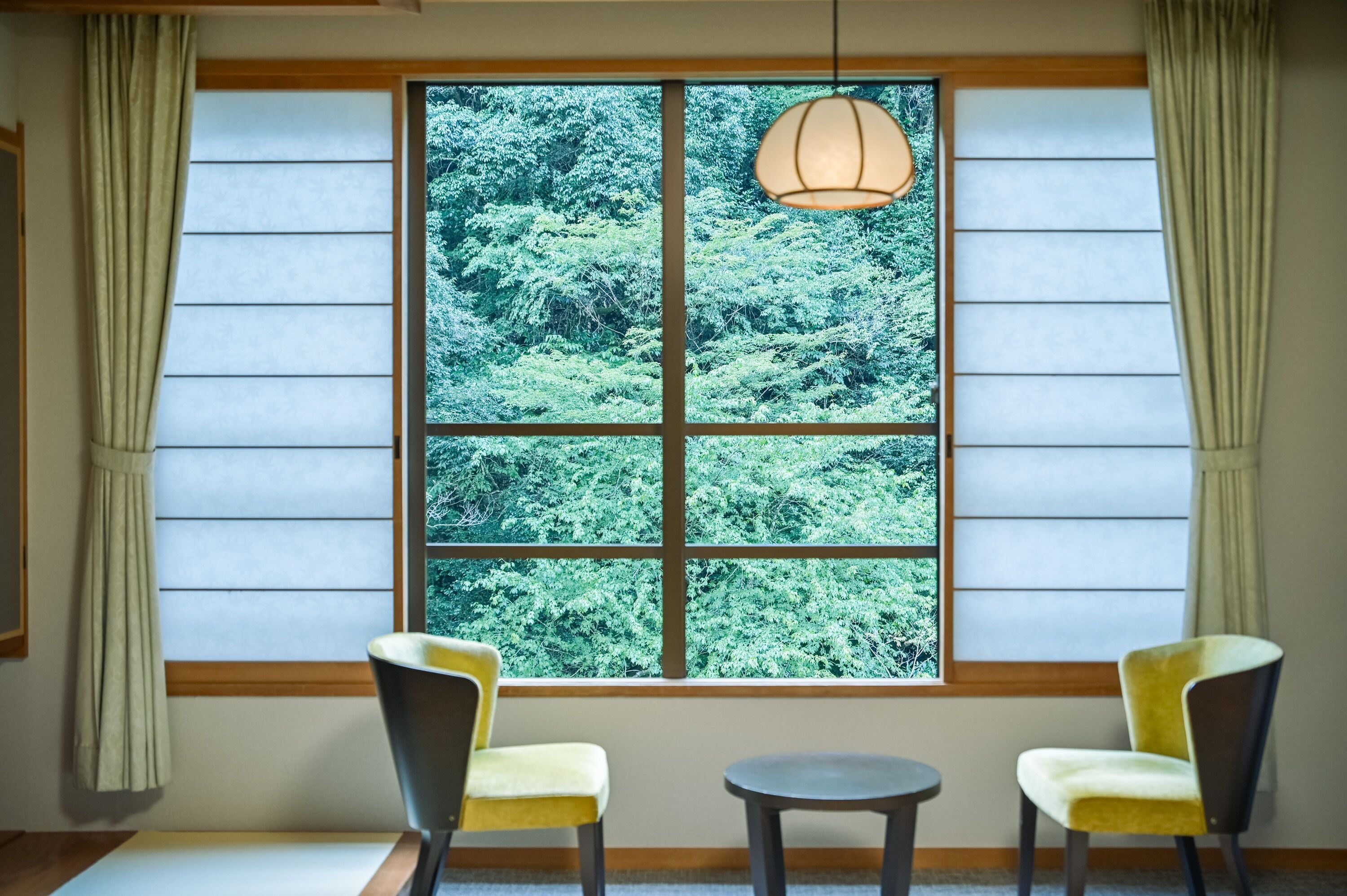 A room with a large window, two chairs, and a small table.