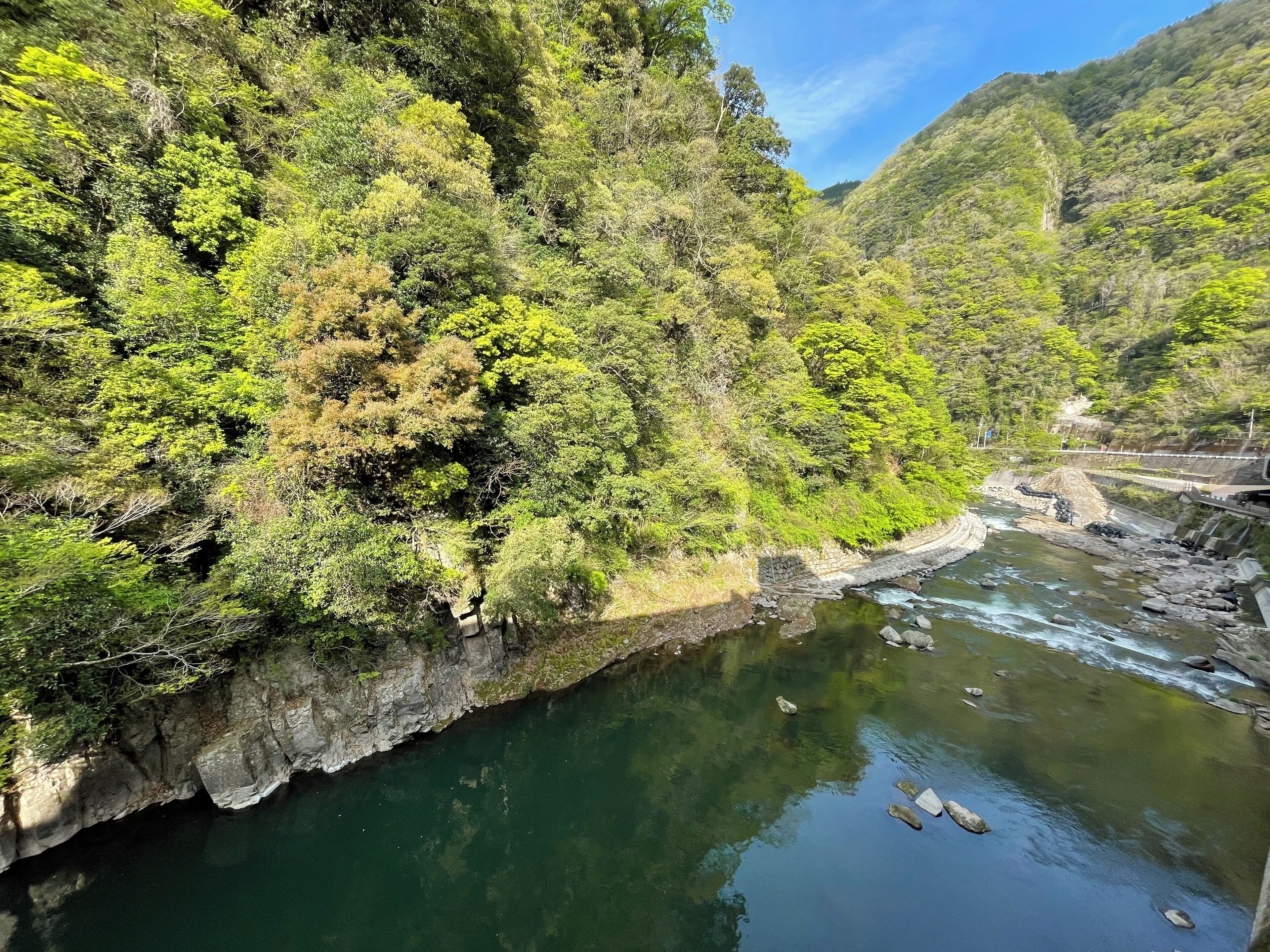 A river flowing through a forested valley with a bridge crossing over it.