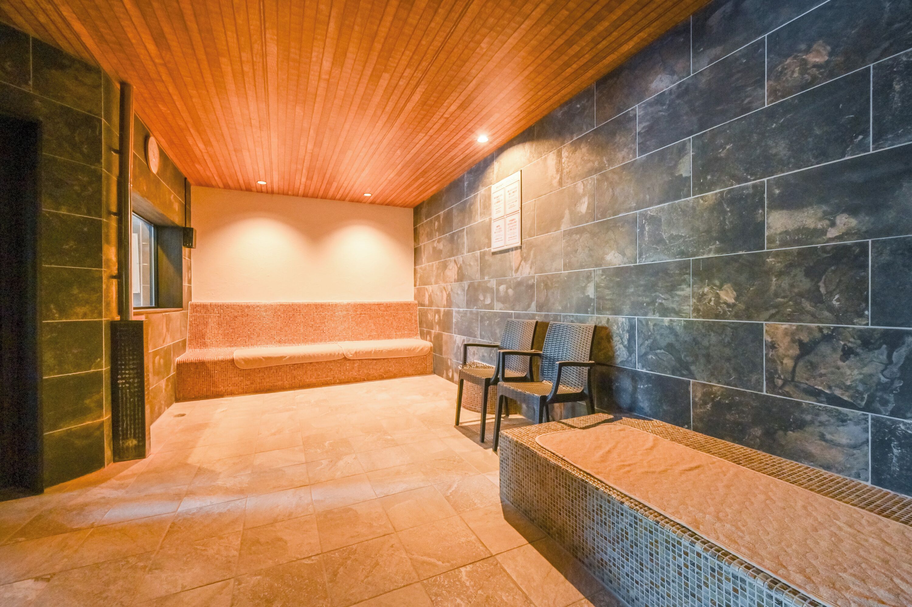 Un área de spa con techo de madera, paredes de piedra y un banco.