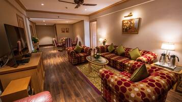 A hotel living room with a sofa set, a coffee table, a TV, and a desk.