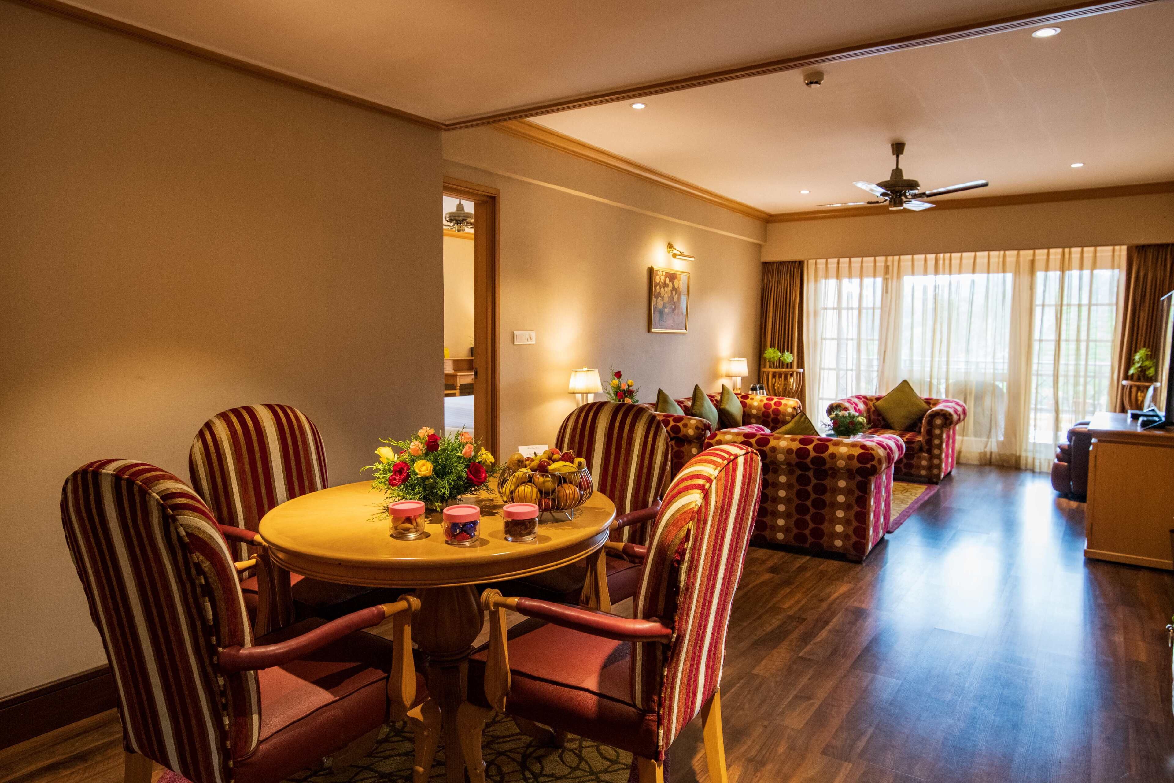 A dining area with a round table and striped chairs, a sofa, and a ceiling fan.