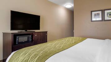 Una habitación de hotel con una cama, un televisor de pantalla plana, un microondas y un armario.