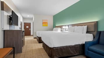 Quarto de hotel com duas camas, uma mesa, uma cadeira, uma televisão e um quadro na parede.