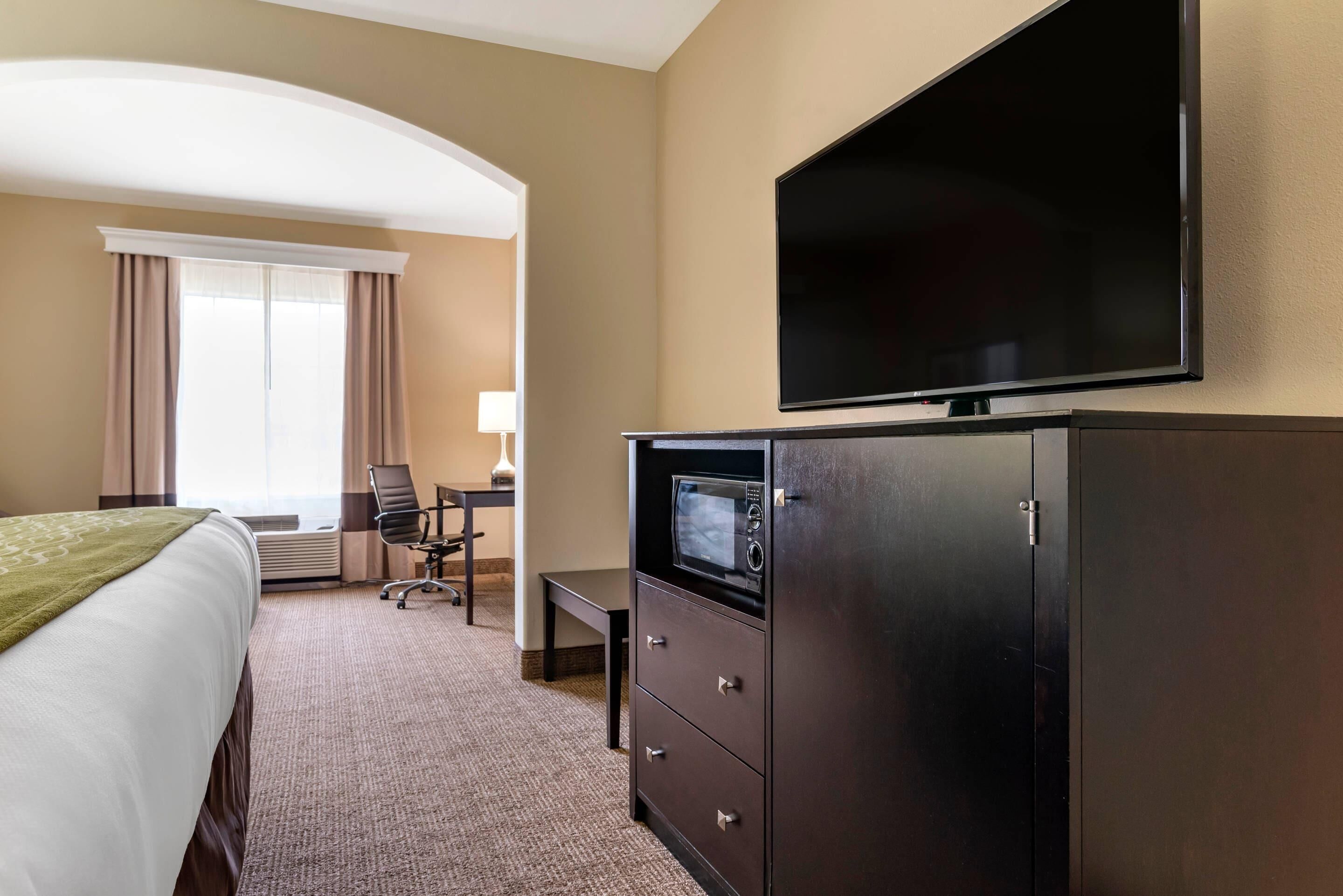 A hotel room with a bed, a desk, a television, and a microwave.
