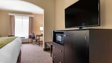 A hotel room with a bed, a desk, a television, and a microwave.