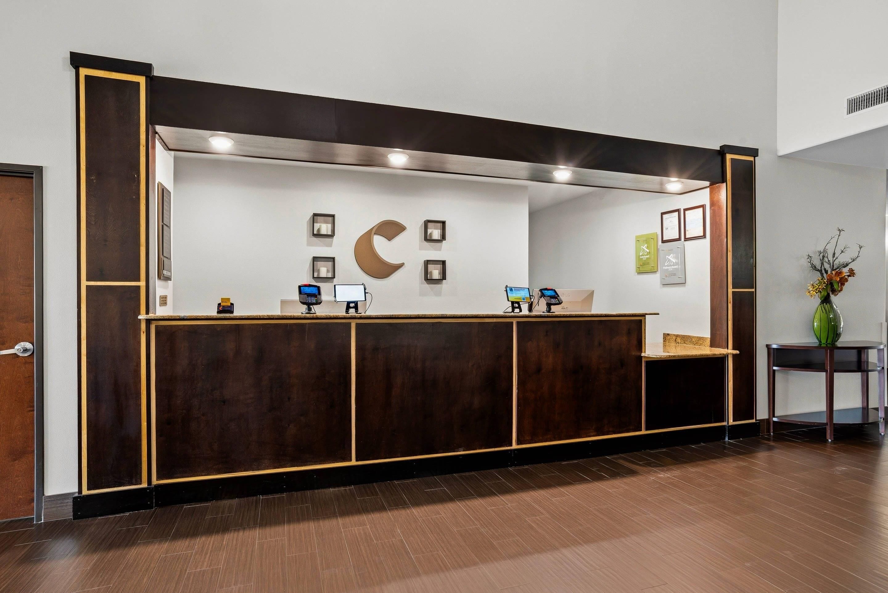 A reception desk with a wooden finish, a large wall-mounted crescent moon decoration, and several framed certificates on the wall.