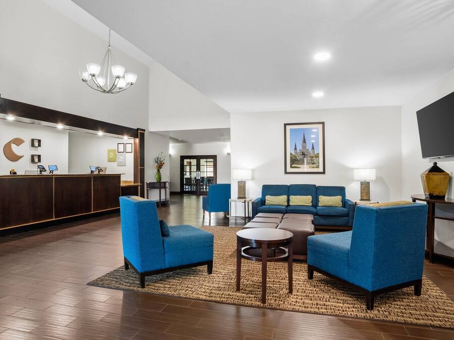Un vestíbulo de hotel con una mesa de recepción, una zona de estar y un cuadro grande en la pared.