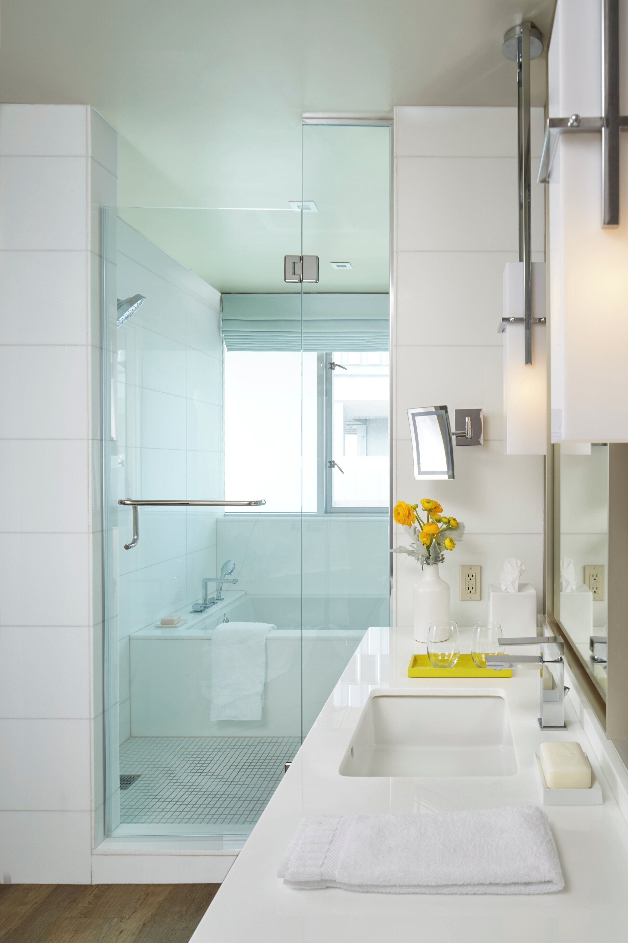 Ein modernes Badezimmer mit einer Duschkabine aus Glas, einem weißen Waschbecken und einem Spiegel darüber.