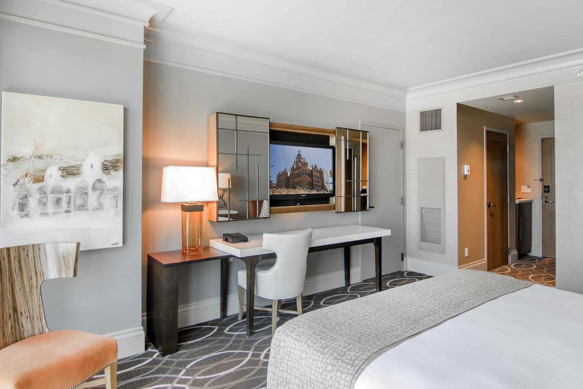 Ein Hotelzimmer mit einem Bett, einem Schreibtisch mit Stuhl, einem Fernseher und einem Bild an der Wand.