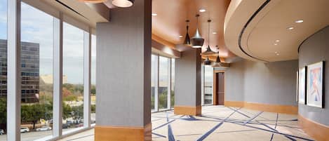 A spacious lobby with large windows, modern pendant lighting, and a patterned carpet.