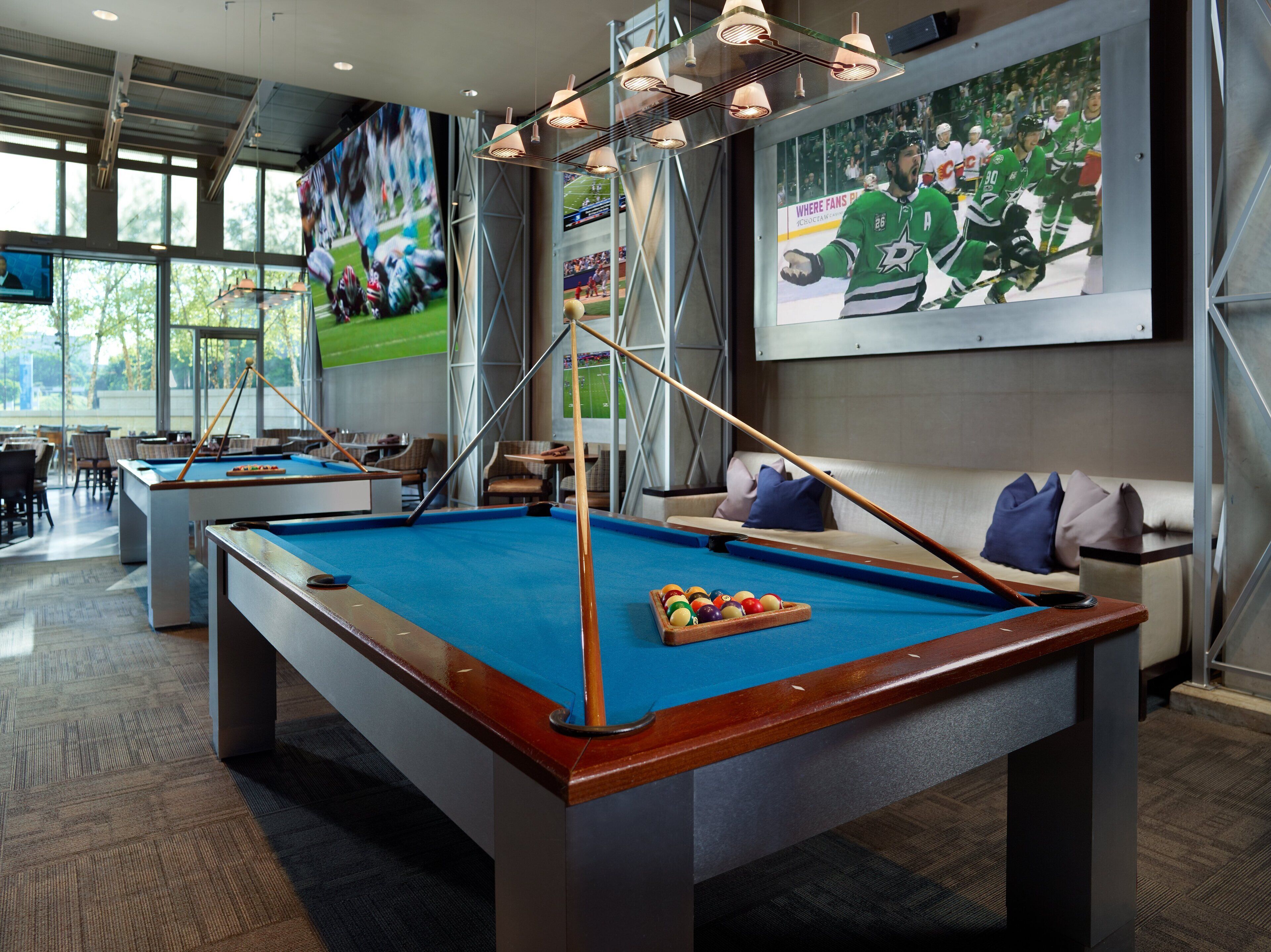 A pool table with a billiard cue, a sofa, and a large sports poster on the wall.