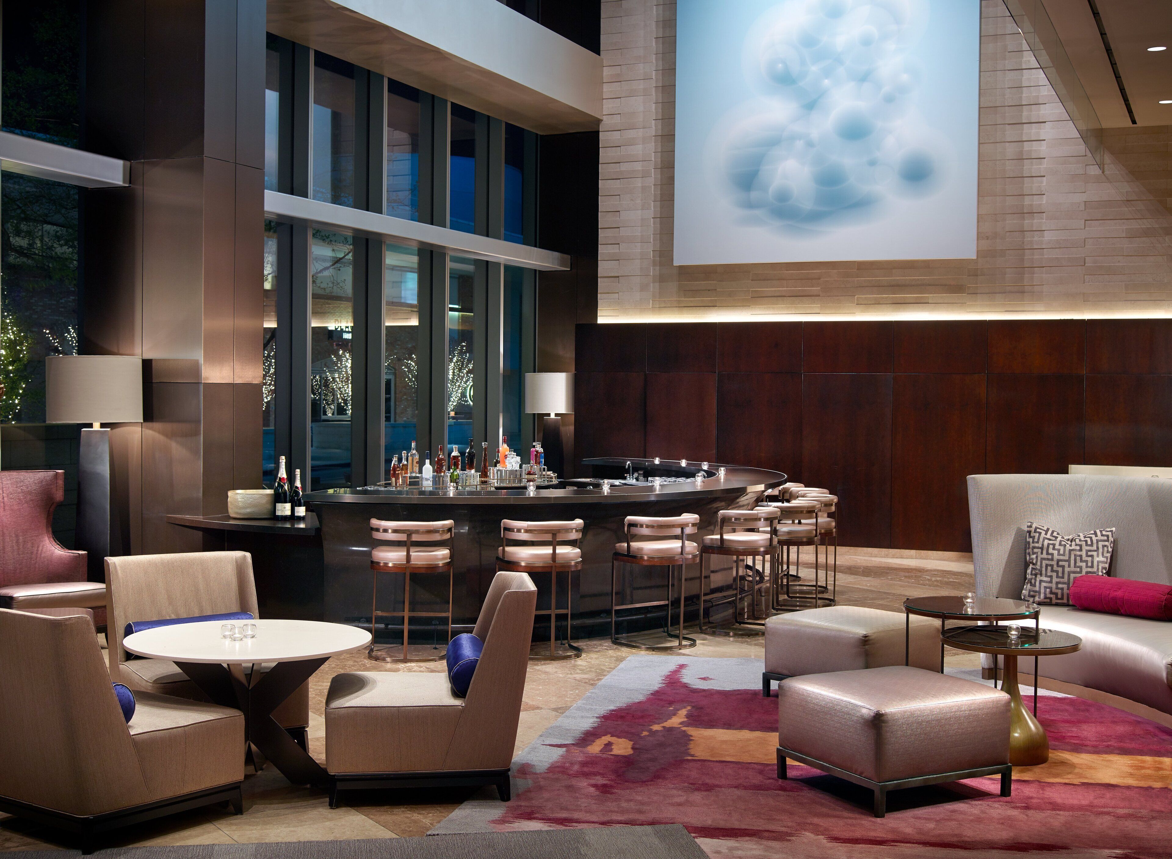 A modern bar area with a bar counter, seating, and a large screen displaying a cloud image.