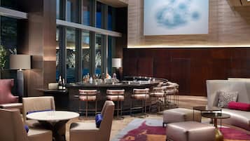 A modern bar area with a bar counter, seating, and a large screen displaying a cloud image.