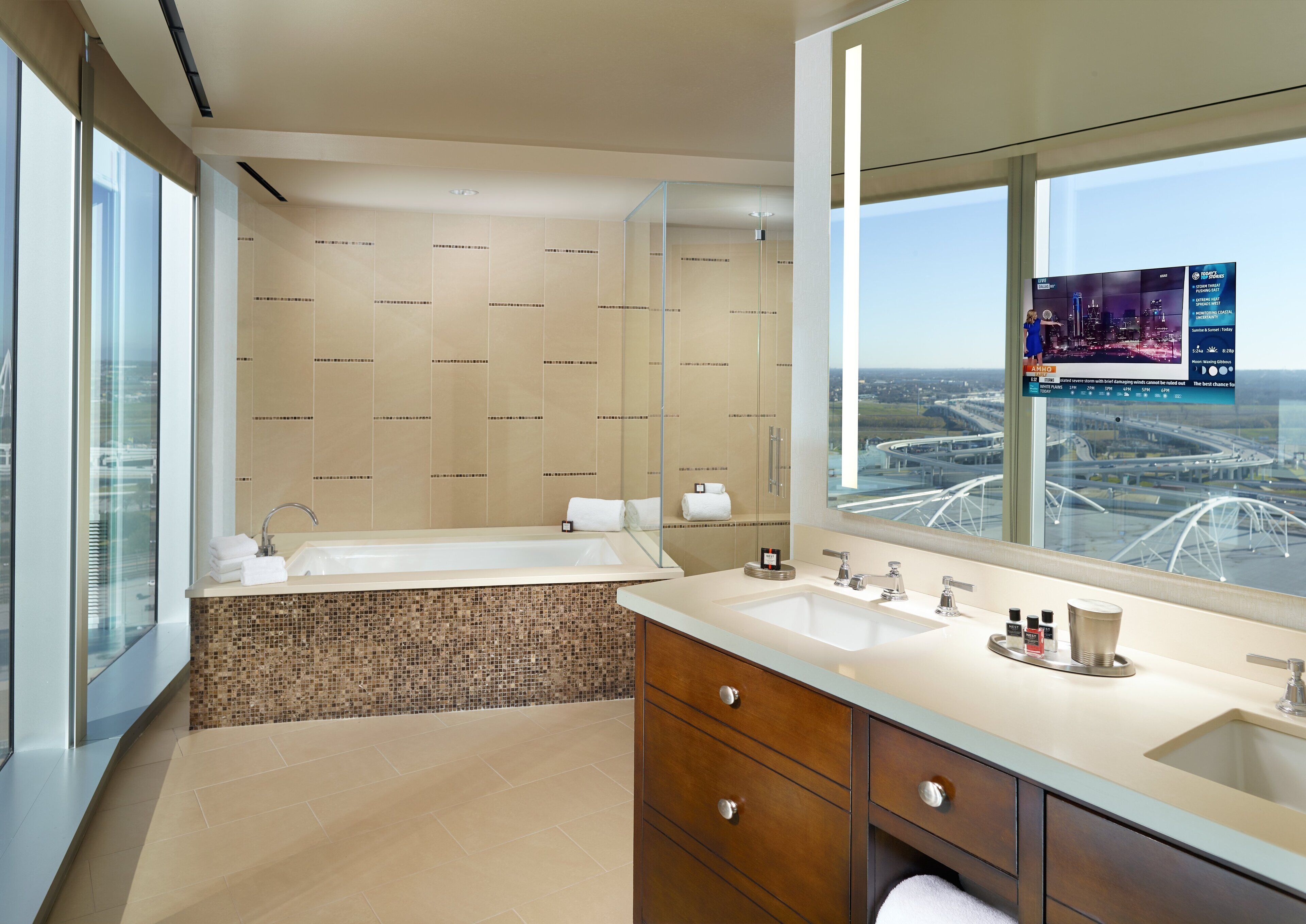A modern bathroom with a large bathtub, a vanity with two sinks, and a large mirror.
