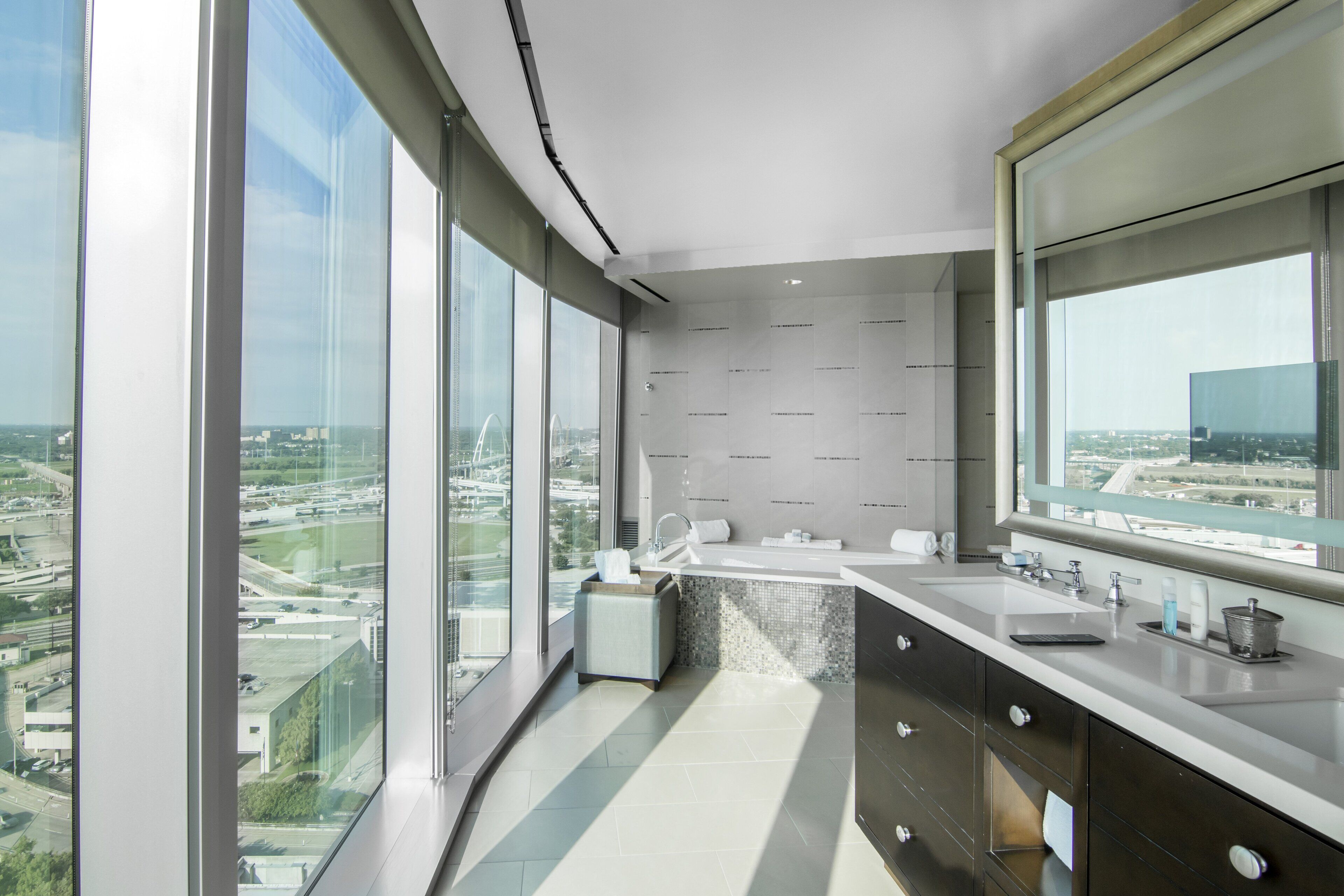 A modern bathroom with a large window, a sink, and a mirror.