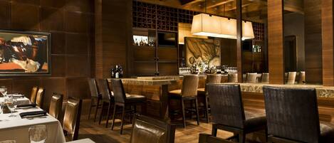 A restaurant with wooden decor, a bar area, and a dining section with tables and chairs.