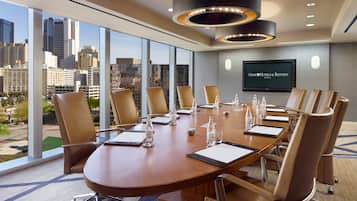 Un salón de conferencias con una gran mesa, sillas y vistas a la ciudad.