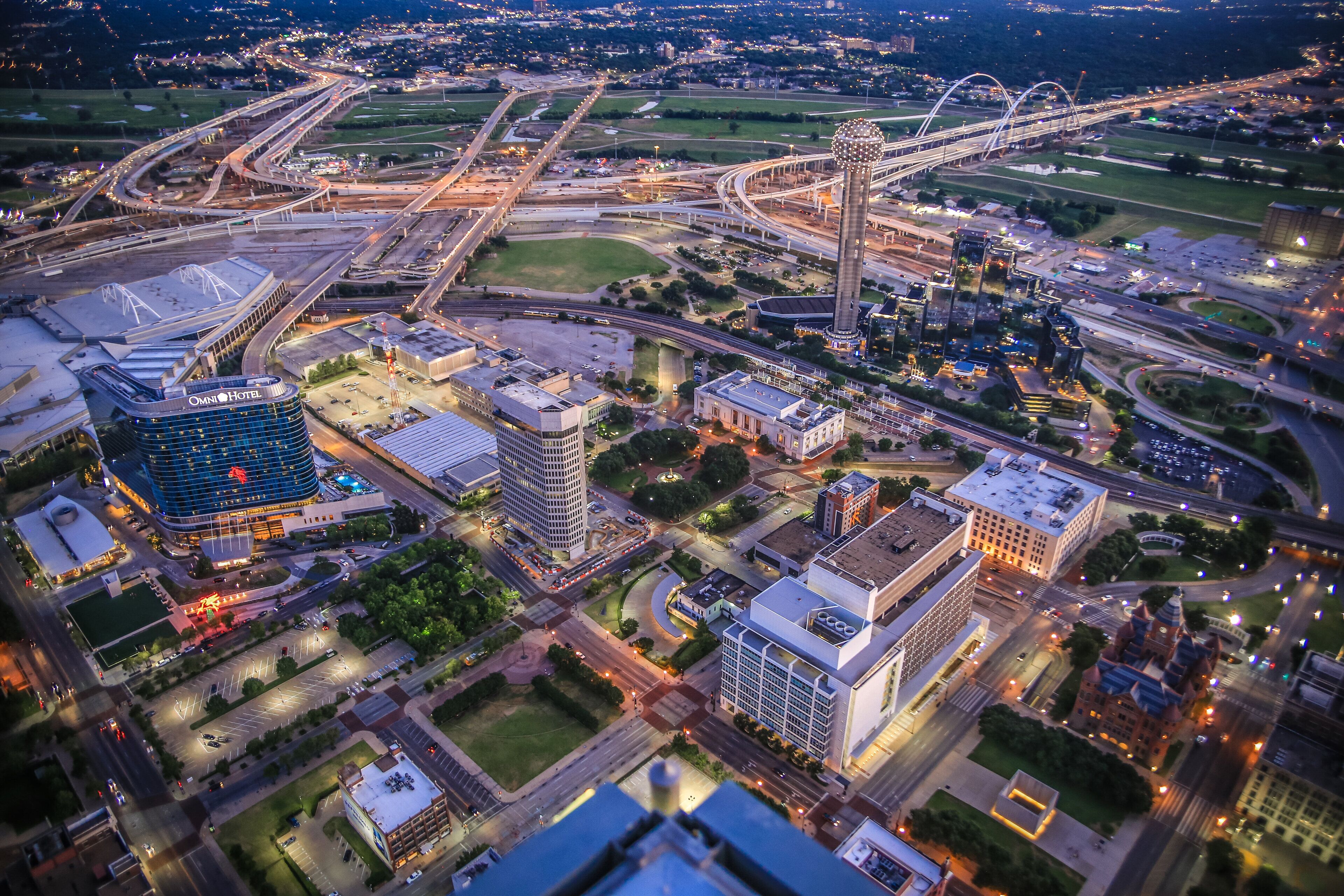An aerial view of a cityscape with a prominent hotel, multiple roads, and bridges.