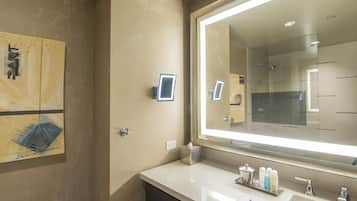 A modern bathroom with a large mirror, a vanity with a sink, and a towel dispenser.