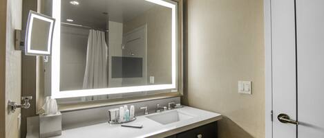 A bathroom with a large mirror, two sinks, a towel rack, and a door.