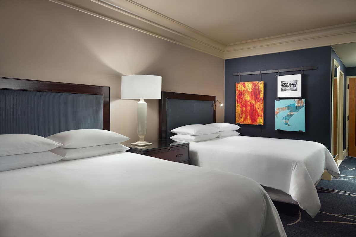 Ein Hotelzimmer mit zwei Betten, einem Nachttisch, einer Lampe und Bildern an der Wand.
