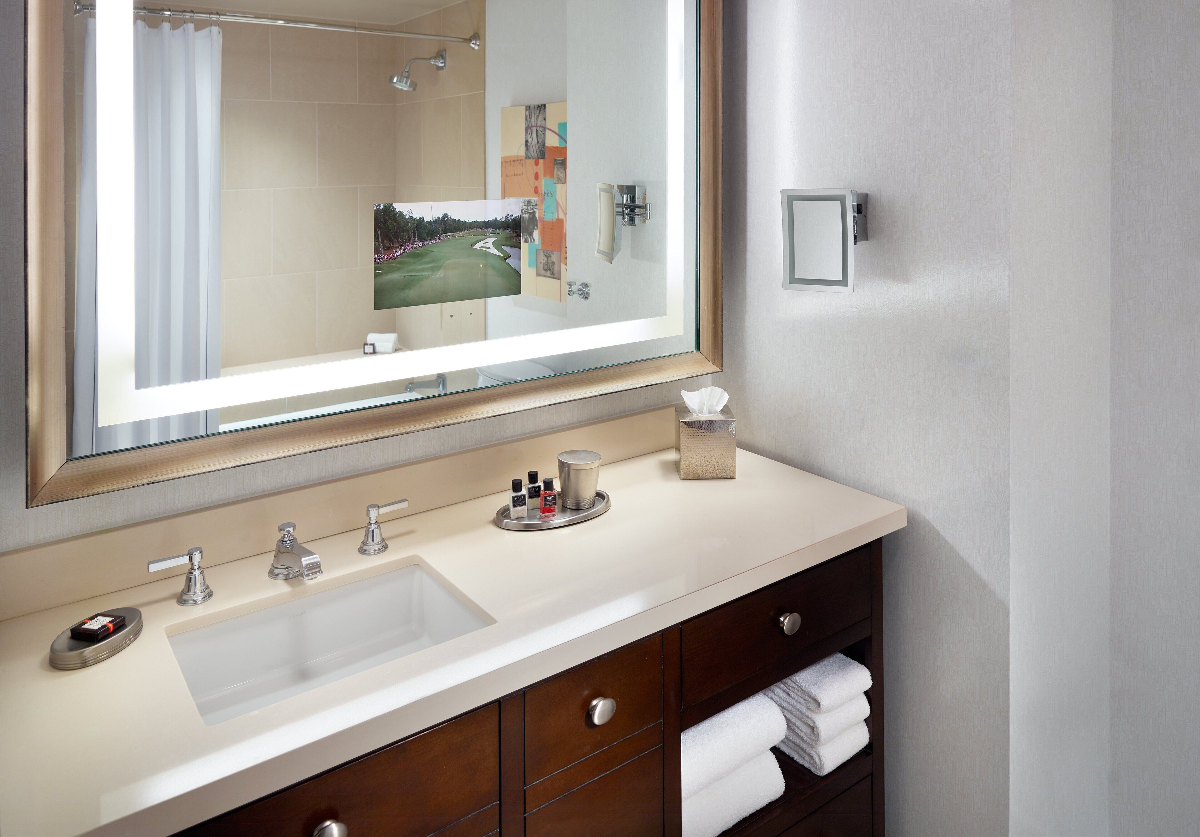 Une salle de bain avec un grand miroir, un lavabo et un porte-serviettes.