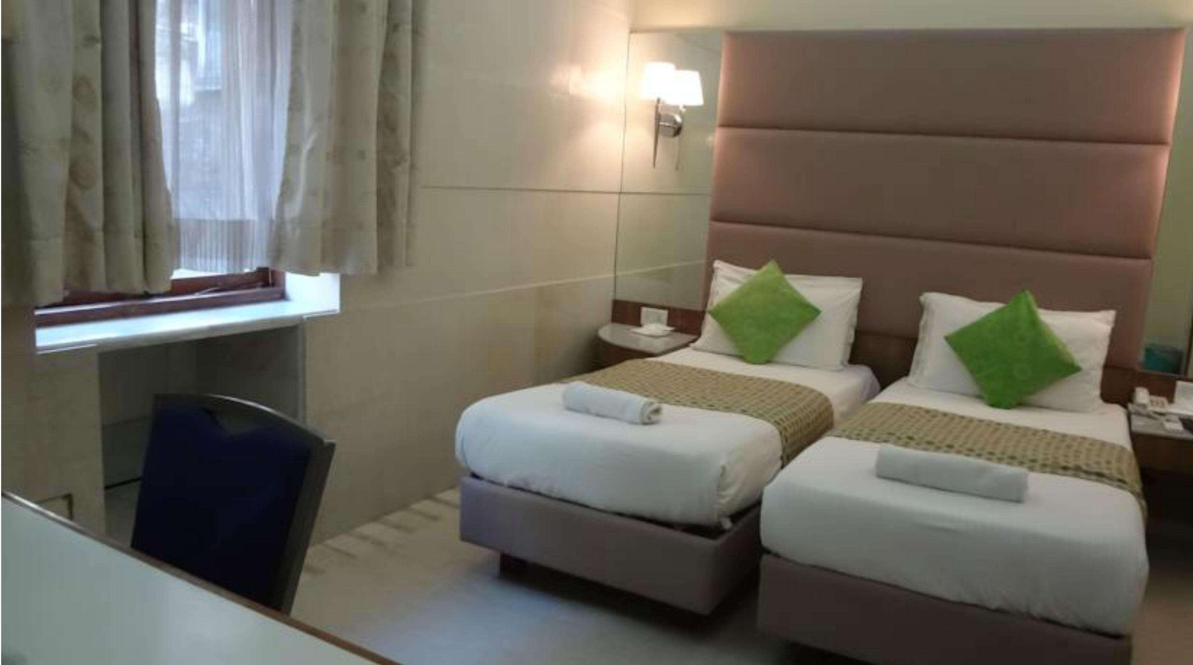 A hotel room with two beds, a desk, and a chair.