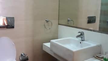 A bathroom with a toilet, sink, and mirror.