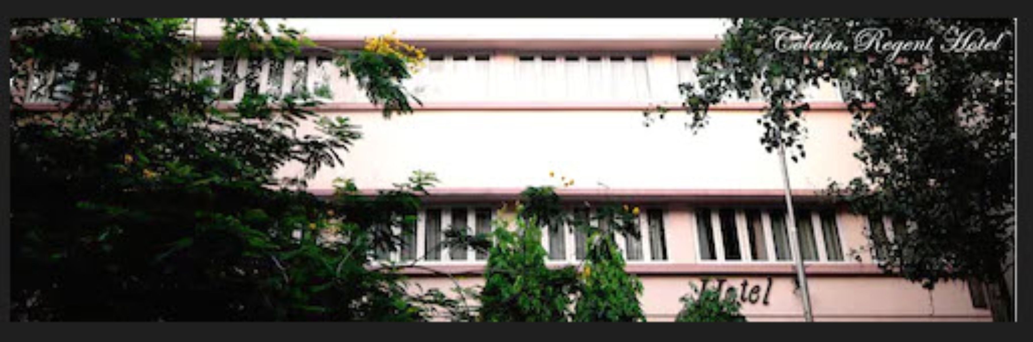 A hotel facade with a pink and white color scheme, featuring a series of windows and a visible sign that reads "Hotel".