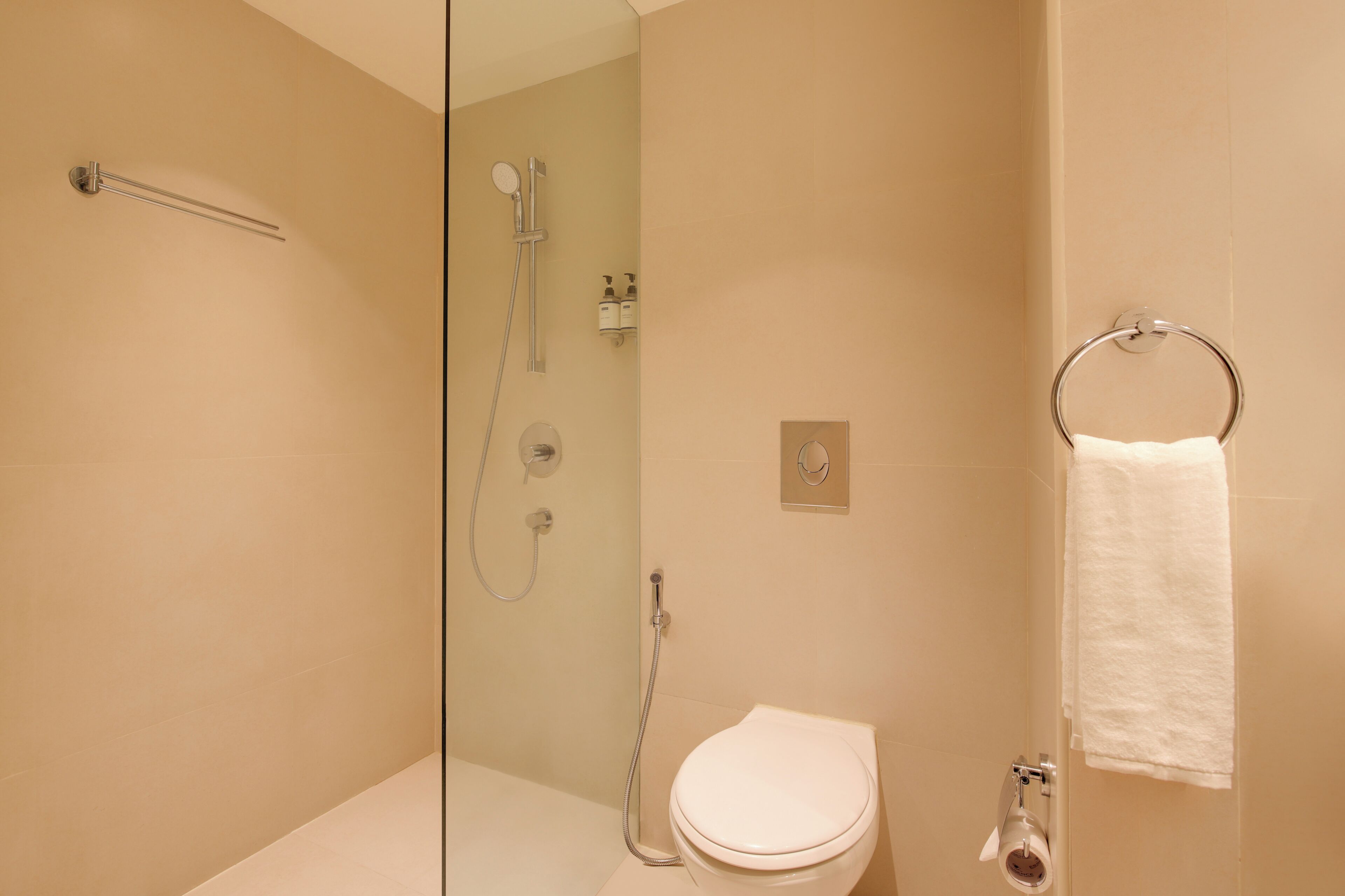 A bathroom with a toilet, a shower, and a towel ring.