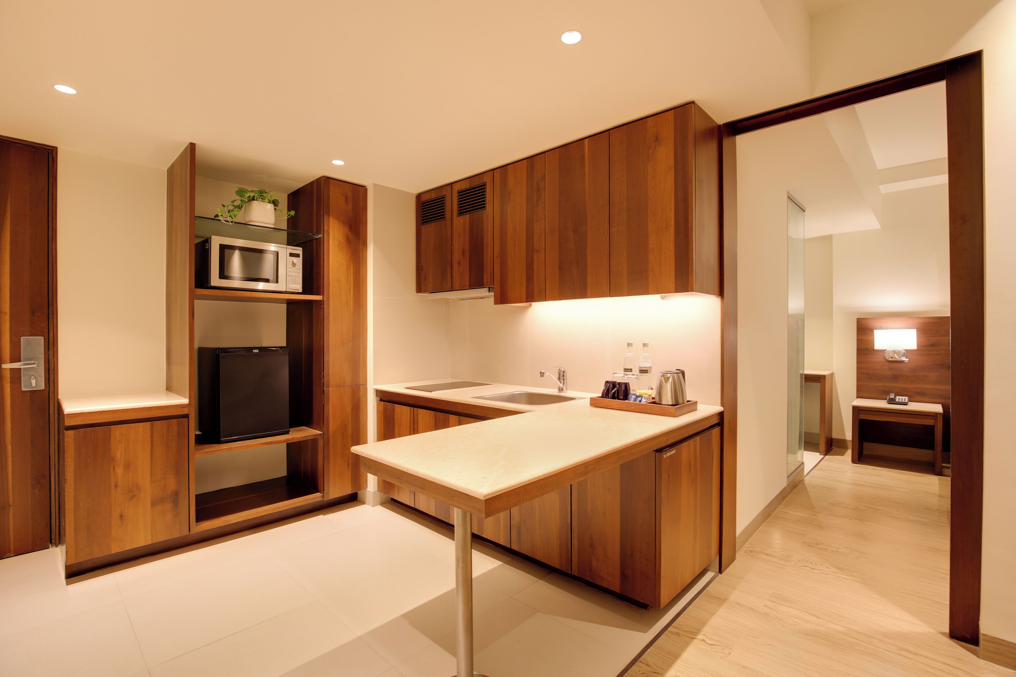 Una cocina moderna con armarios de madera, un microondas, un refrigerador y un lavamanos.