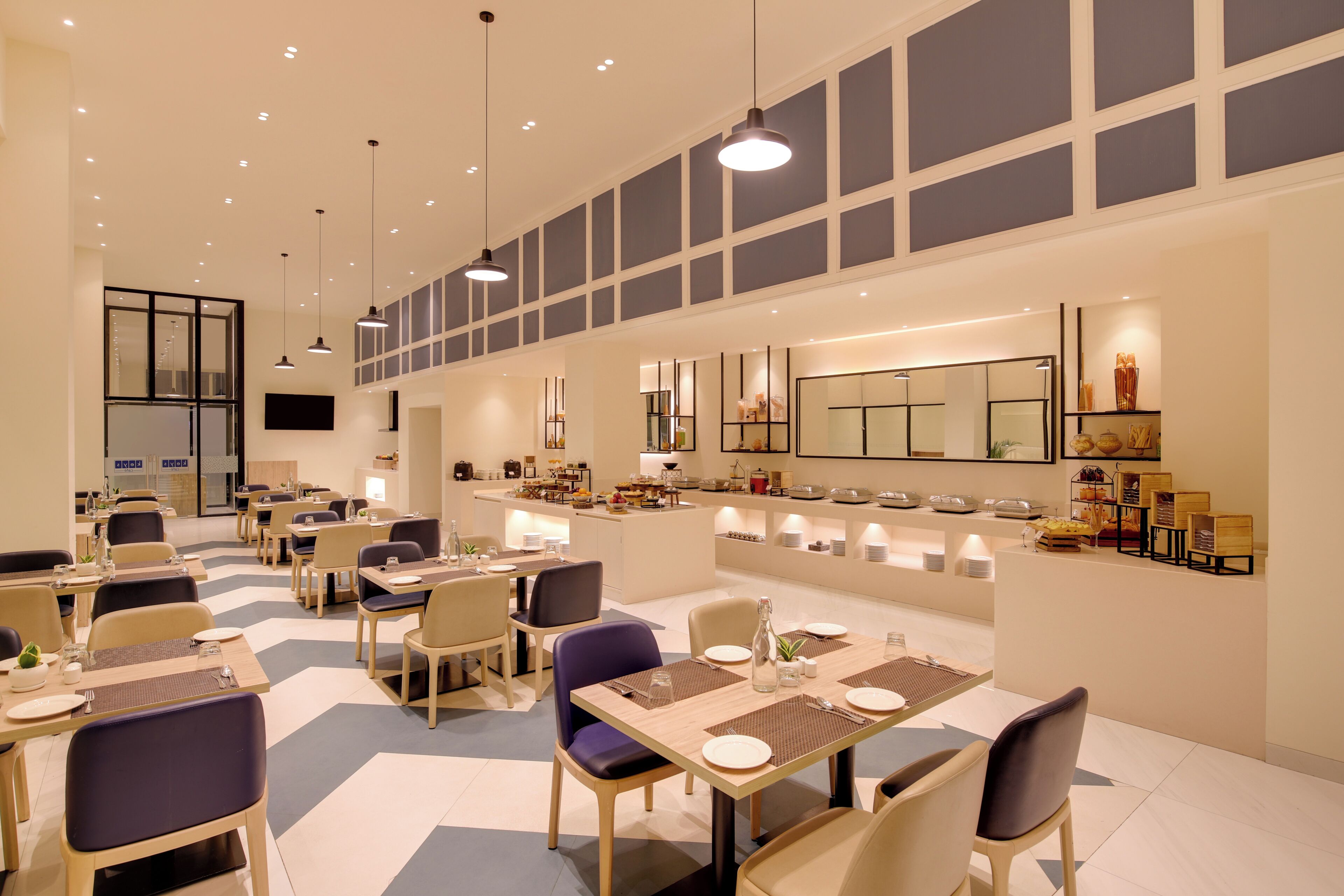 A modern dining area with multiple tables, chairs, and pendant lighting.