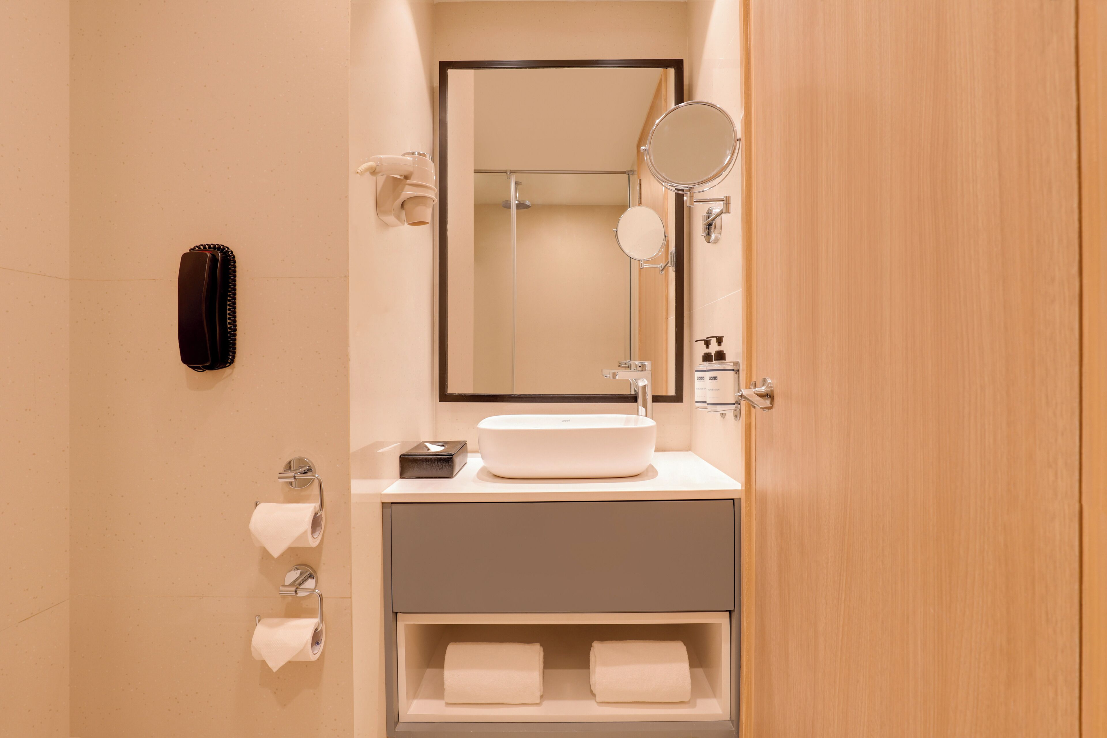 A modern bathroom with a large mirror, a sink, and a towel rack.