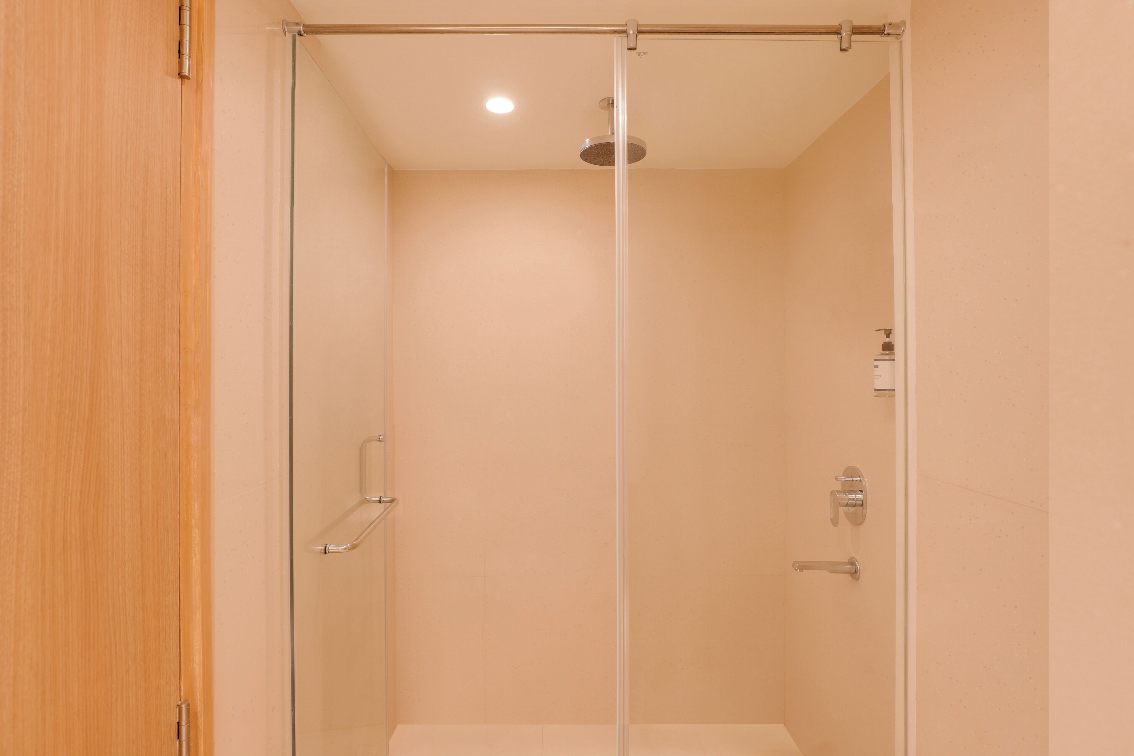 A glass-enclosed shower stall with a showerhead, a towel rack, and a door.