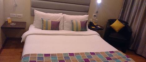 A hotel room with a bed, a nightstand, a telephone, and a lamp.