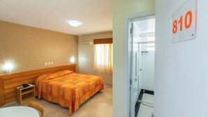 A hotel room with a bed, a chair, a small table, and a door marked with the number 810. - Confort Hotel (Sao Leopoldo)