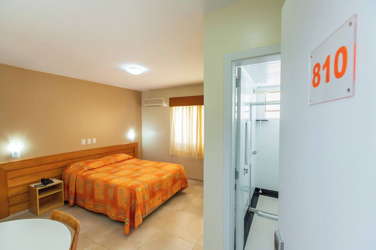 Ein Hotelzimmer mit einem Bett, einem Sessel, einem kleinen Tisch und einer Tür mit der Nummer 810.