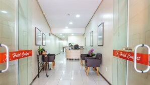 A hotel reception area with a reception desk, chairs, and potted plants. - Confort Hotel (Sao Leopoldo)