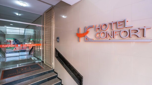 A hotel entrance with a sign reading "HOTEL CONFORT" and a staircase leading to the lobby. - Confort Hotel (Sao Leopoldo)